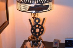 V8 themed lamp, motorcycle cover for base, Plymouth hubcap, Chrysler Cordoba hood ornament as finial.