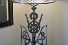 Art Deco gate themed lamp. 1965 Chevy SS hubcap shade. Activated via touch switch. This lamp took second place at the 2019 Orange County Fair in the upcycled category. It also won the green award and 2 other awards.