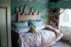 Castle daybed with matching tree shelves and mural on all walls.